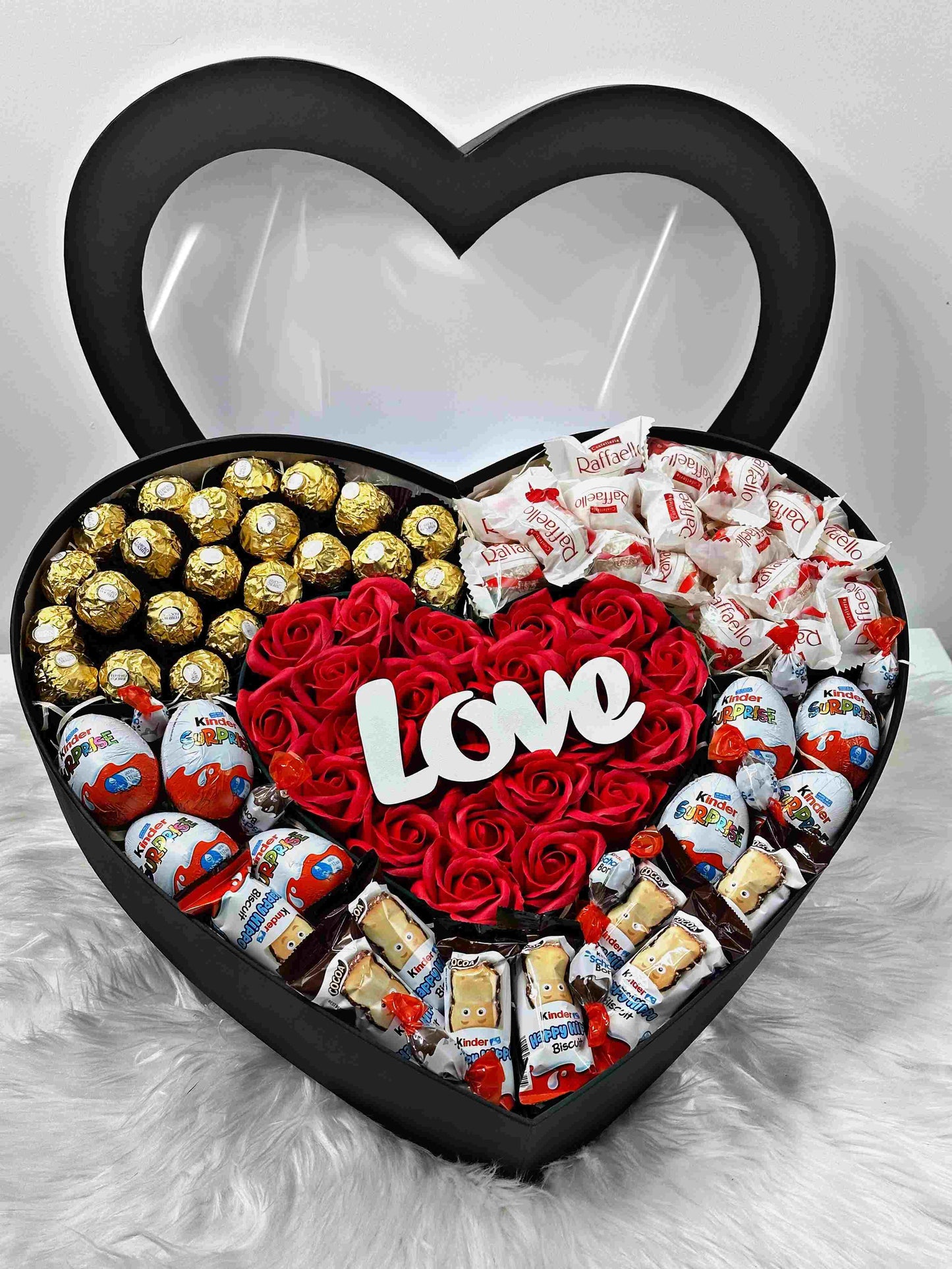 Large black heart-shaped gift box with 25 soap roses, 28 Ferrero Rocher chocolates, 12 Raffaello candies, and a selection of Kinder sweets, including Kinder Surprise Eggs, Happy Hippo, and Schoko Bons. A luxurious and elegant gift for special occasions like birthdays, anniversaries, or romantic celebrations.