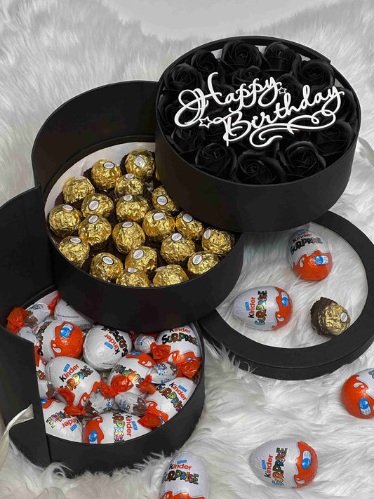 Three-tiered black gift box with 21 soap roses, 28 Ferrero Rocher chocolates, and a selection of Kinder treats, including Surprise Eggs and Schoko Bons. A luxurious gift for any celebration.