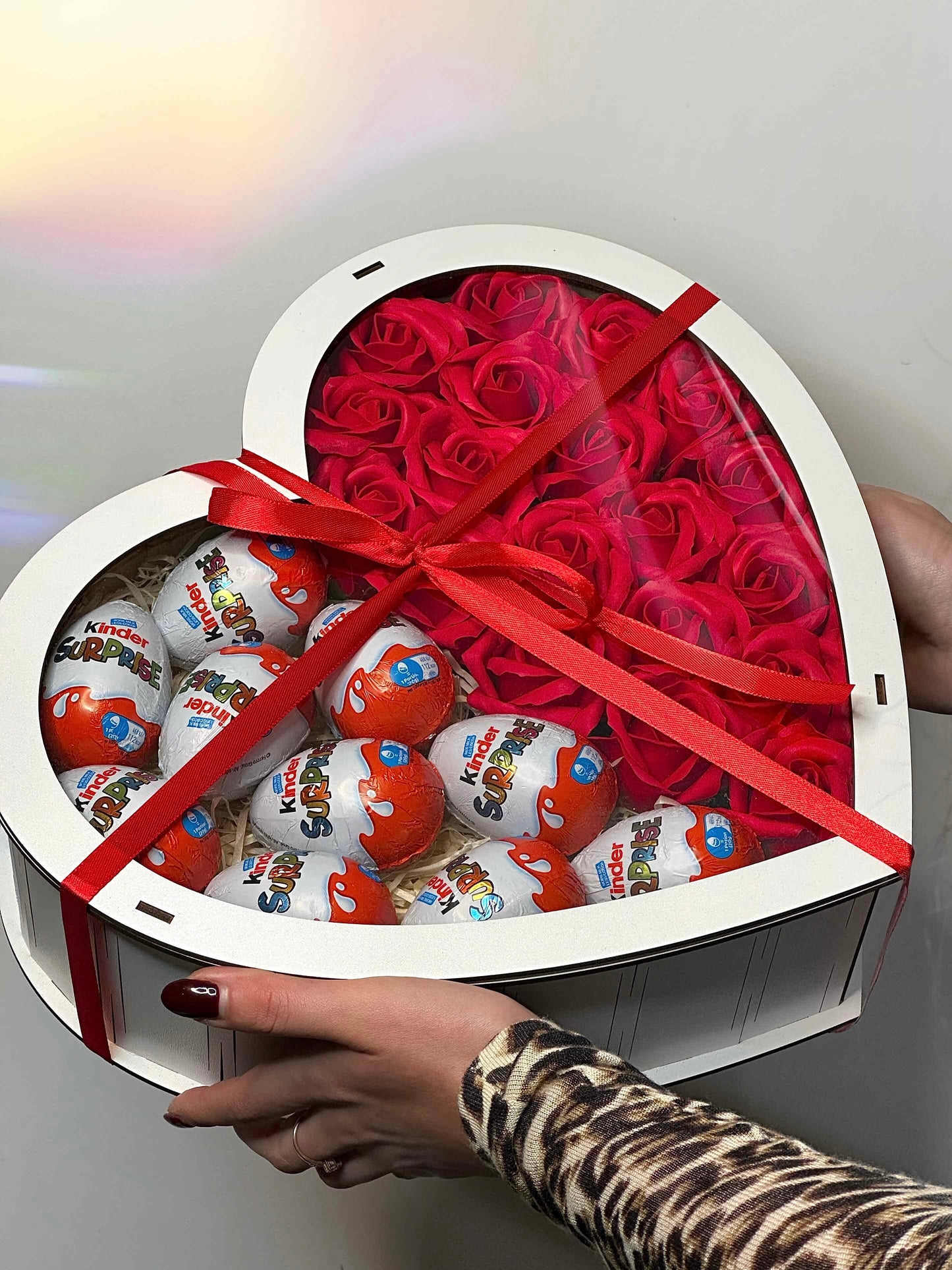 Close-up of Kinder Surprise eggs arranged in the white wooden heart-shaped gift box, highlighting the sweet treat included in this elegant present.